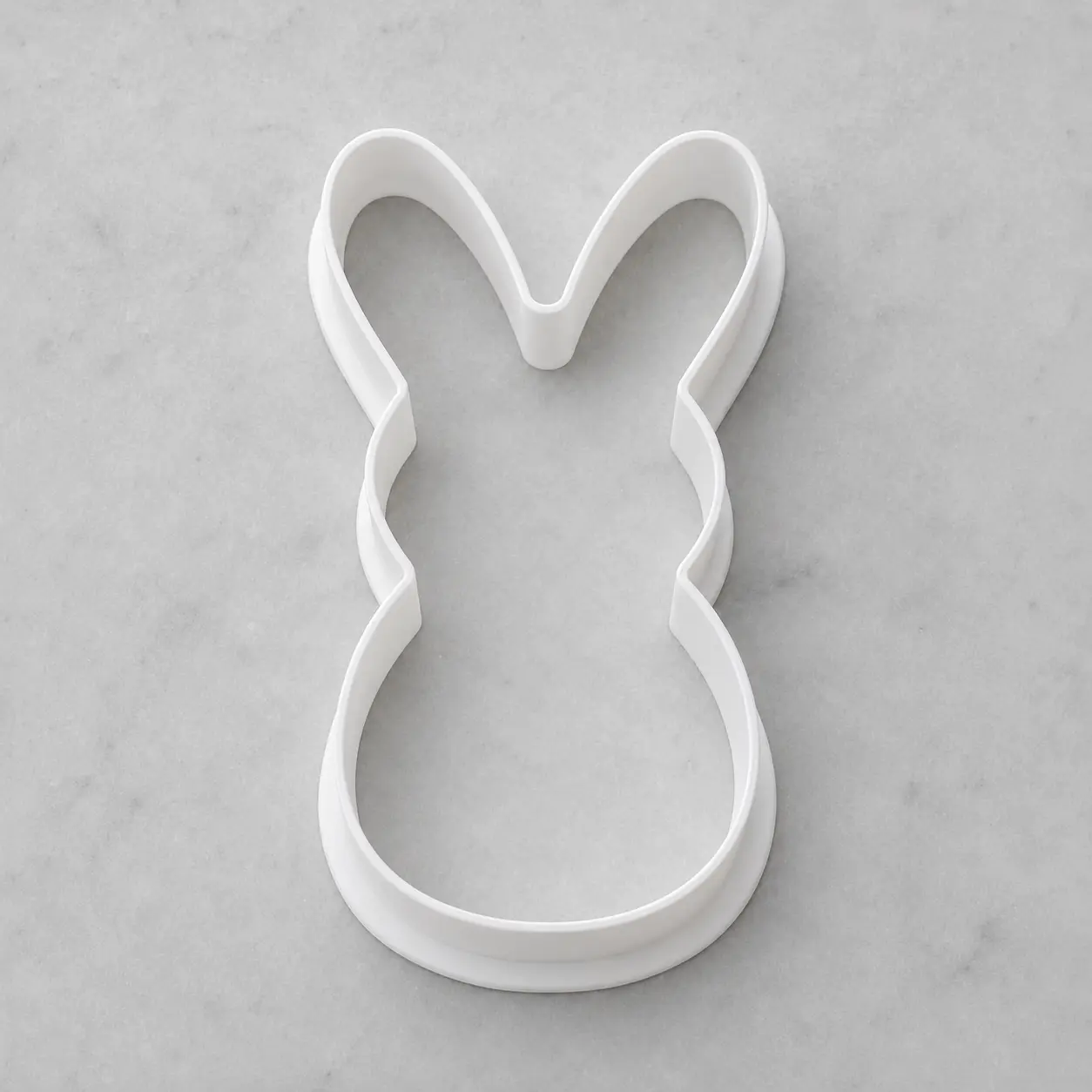 Custom-shaped cookie cutter cutting a cookie into a unique silhouette.